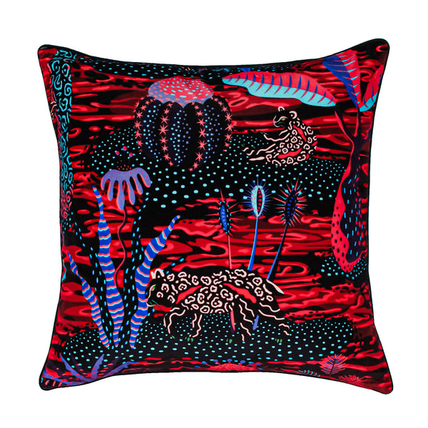 Bold red Quandary Quagmire cushion showing lava, panthers and prickly vegetation.